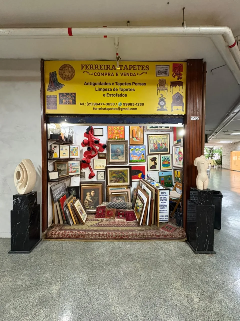 Entrada da Ferreira Tapetes com quadros, obras de arte e tapetes expostos